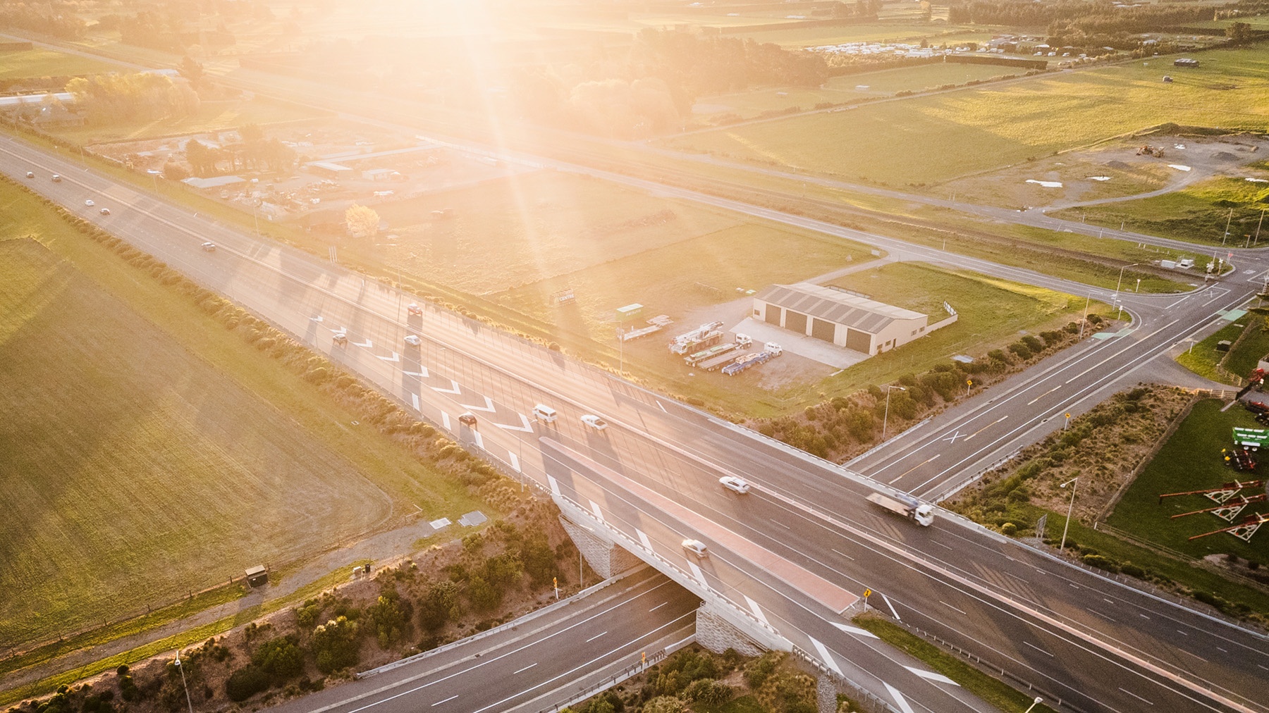 Aerial view of a motorway interchange crossing rural land, with vehicles travelling on multiple roads.
